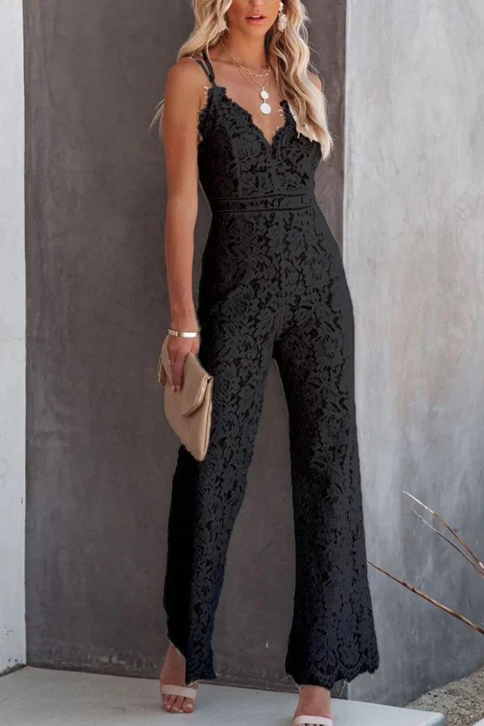 Woman wearing black lace sleeveless jumpsuit with v-neck, holding beige clutch, posing indoors