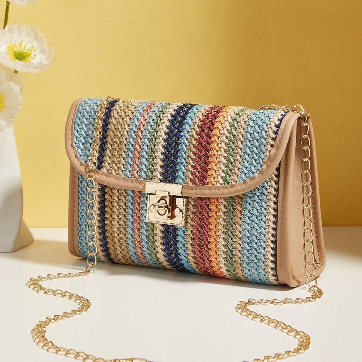 Colorful striped woven crossbody bag with gold chain strap on white surface