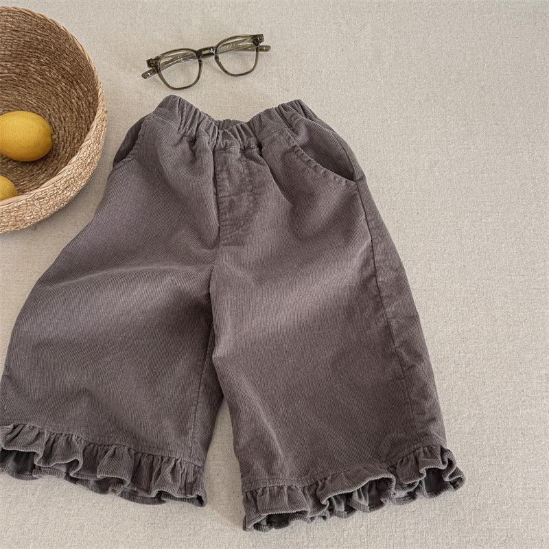 Gray corduroy pants with ruffle hem for kids, elastic waist, styled with eyeglasses and lemons in wicker basket