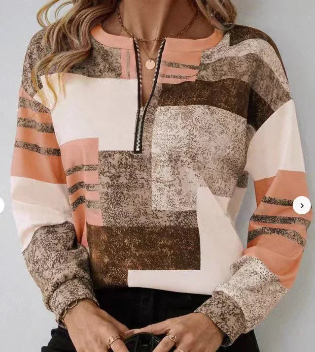 Woman wearing a long-sleeve abstract print zip-up sweater in brown, peach, and cream colors