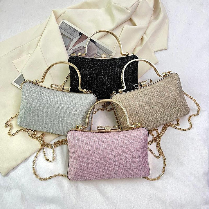 Elegant rectangular clutch handbags in black, gold, silver, and pink with gold chain straps on white fabric