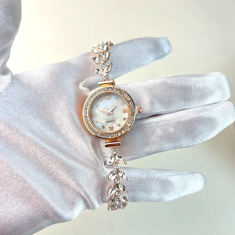 Elegant women's quartz wristwatch with crystal-studded round face and leaf-patterned bracelet held by gloved hand