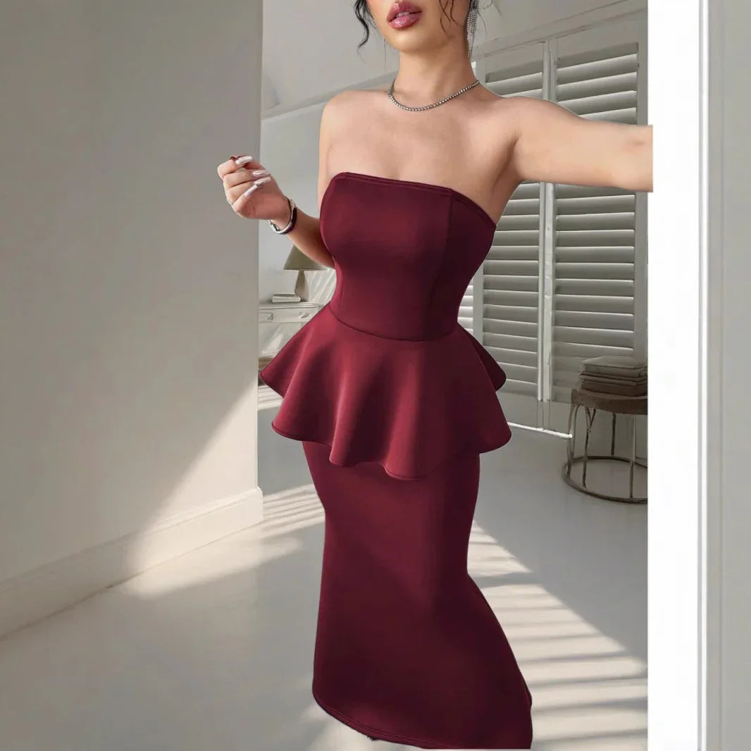 Woman wearing strapless burgundy peplum midi dress in bright room with shutters