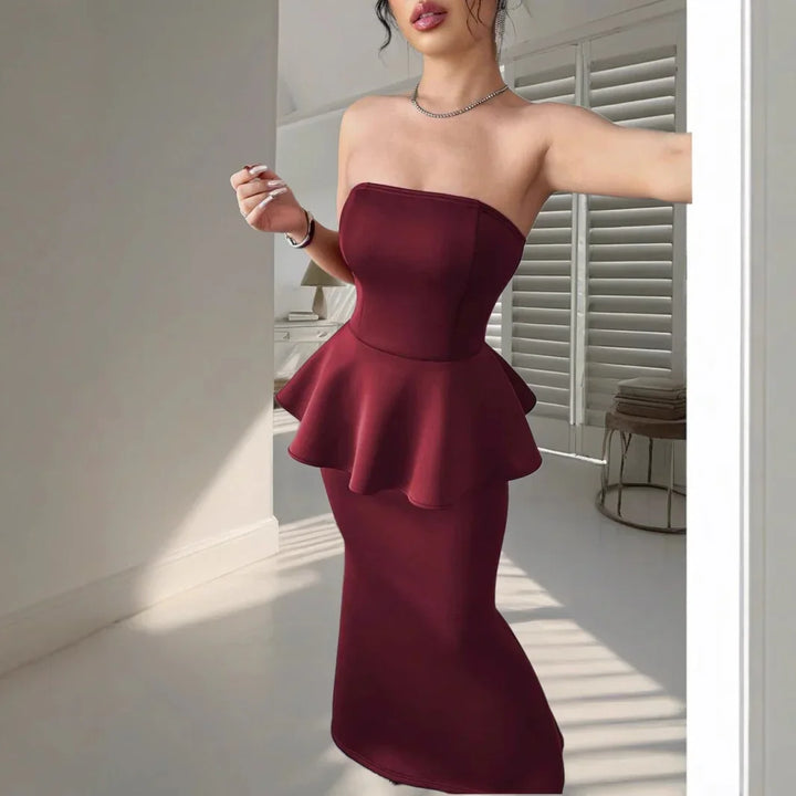 Woman wearing strapless burgundy peplum midi dress in bright room with shutters