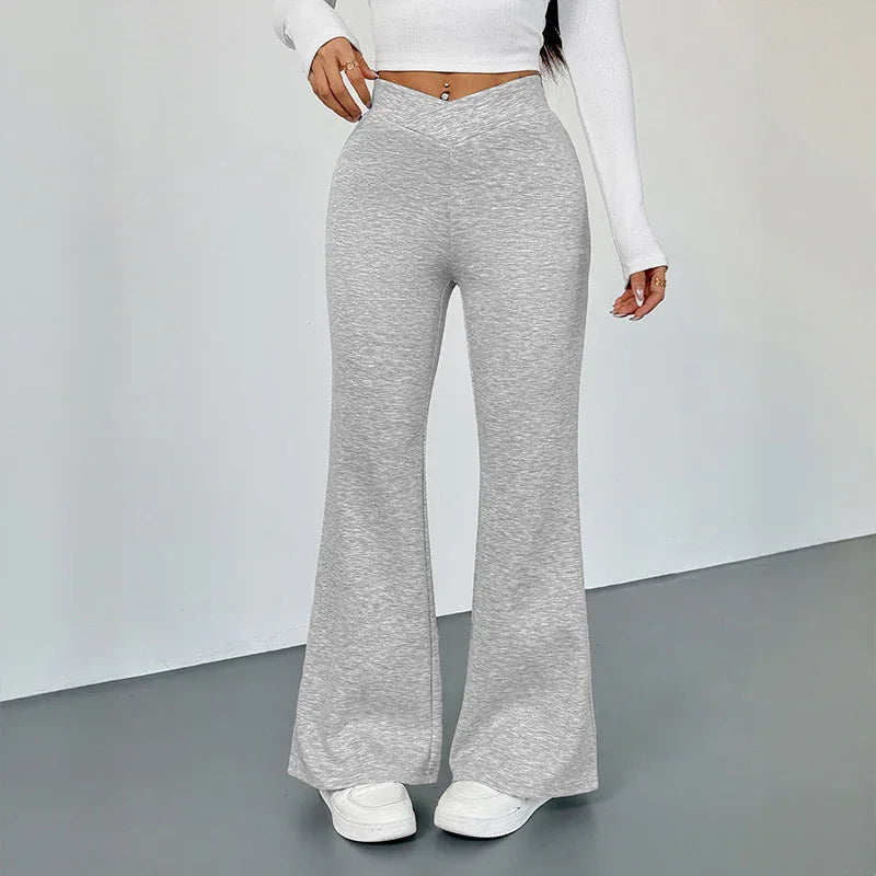 Woman wearing grey high-waisted flare pants and white cropped top with white sneakers