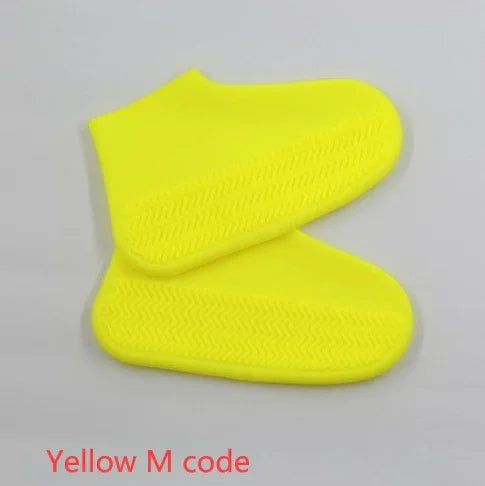 Pair of bright yellow silicone shoe covers with textured soles on a light gray background