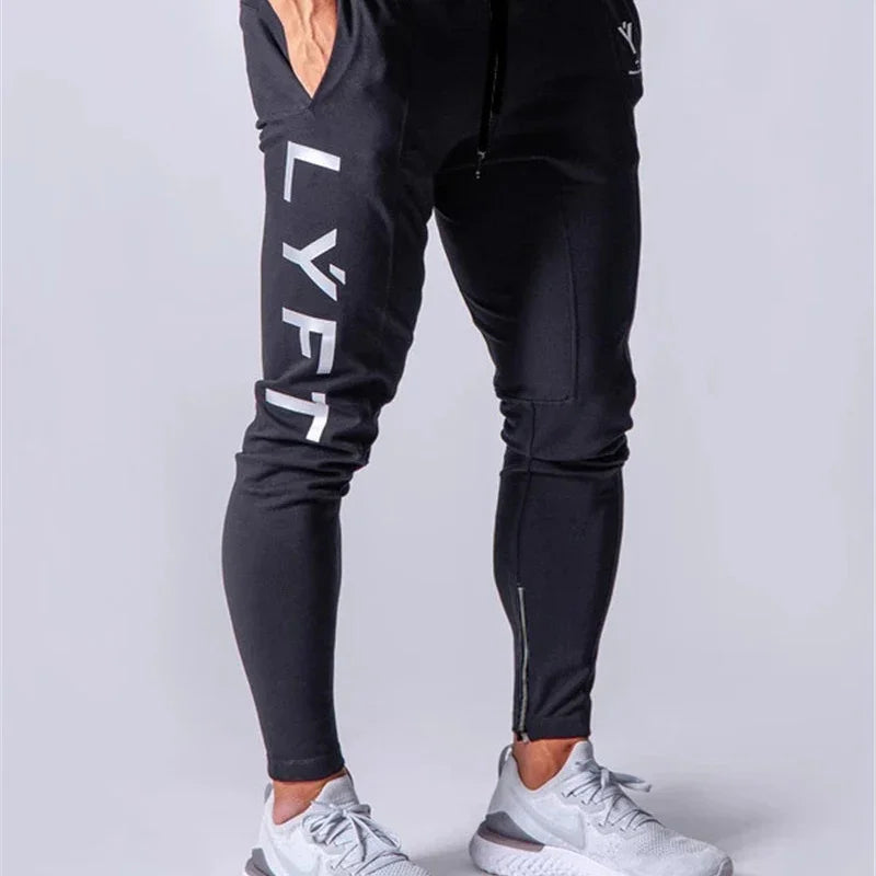 Man wearing black LYFT branded joggers and white athletic sneakers on white background