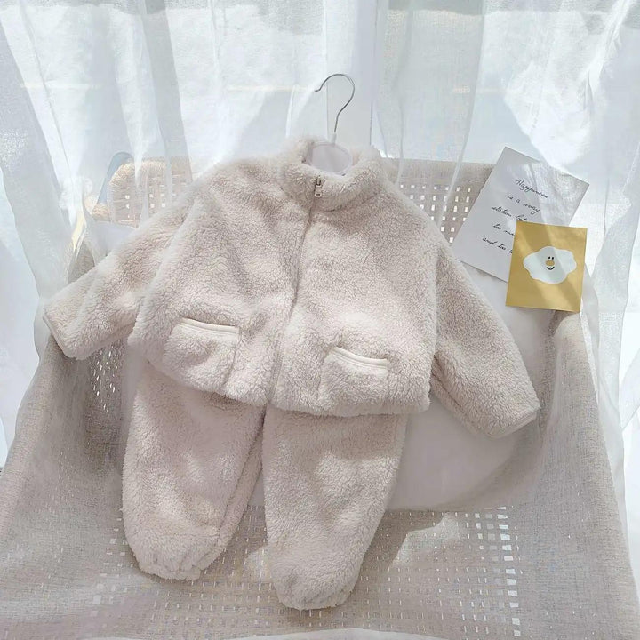 Cozy white fleece baby jacket and pants set on woven chair with soft natural light