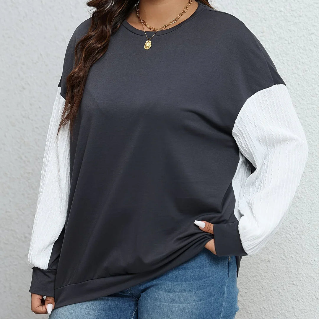 Woman wearing black and white color block long sleeve shirt with textured white sleeves and blue jeans