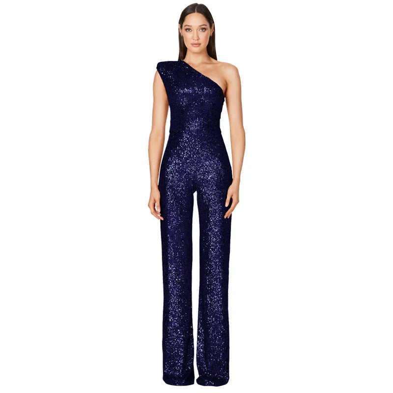 Woman wearing a navy blue one-shoulder sequin jumpsuit with wide-leg pants on white background