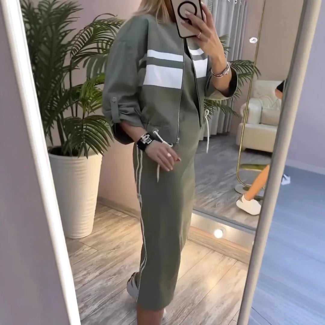 Woman wearing olive green sporty midi dress with white stripes, taking mirror selfie in modern room