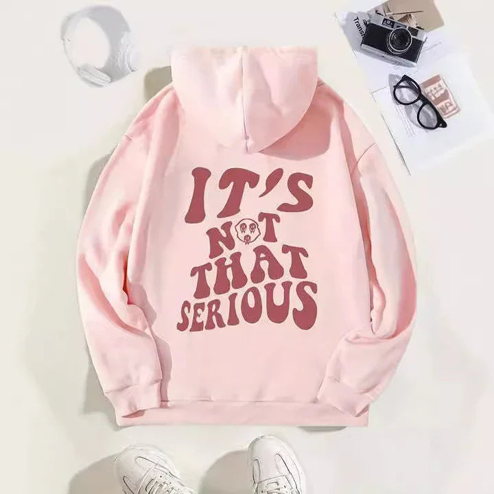 Light pink hoodie with large maroon text saying 'IT'S NOT THAT SERIOUS' and an illustrated skull on the back