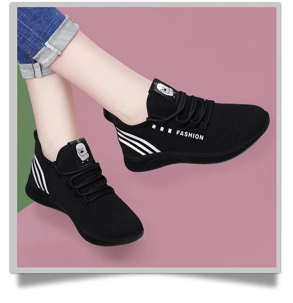 Black casual sneakers with white stripes and cartoon logo worn with rolled-up jeans on pink background