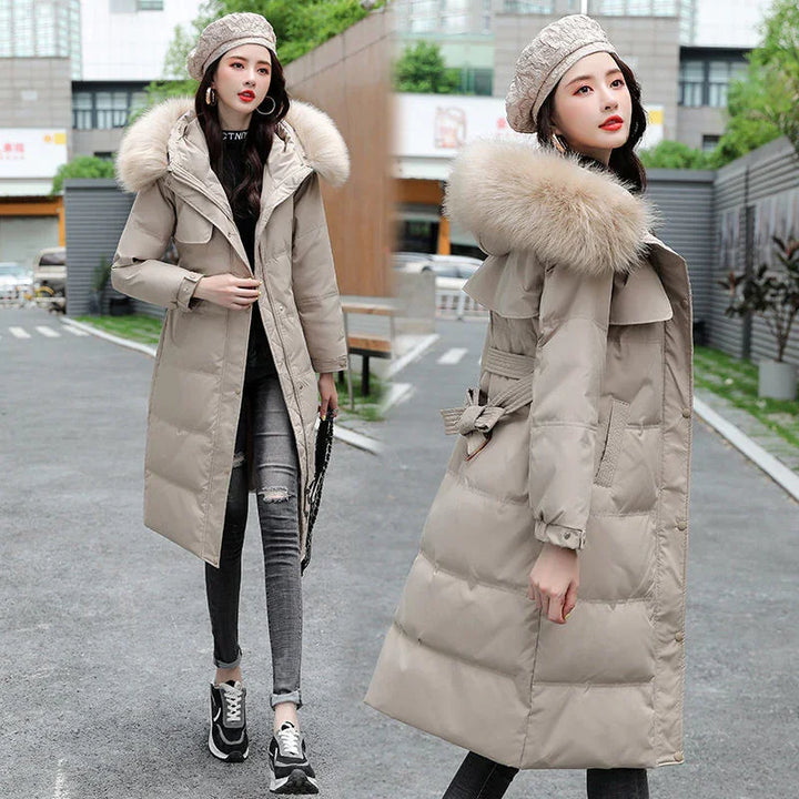 Woman wearing beige long padded winter coat with fur hood and knit beret, posing outdoors on urban street