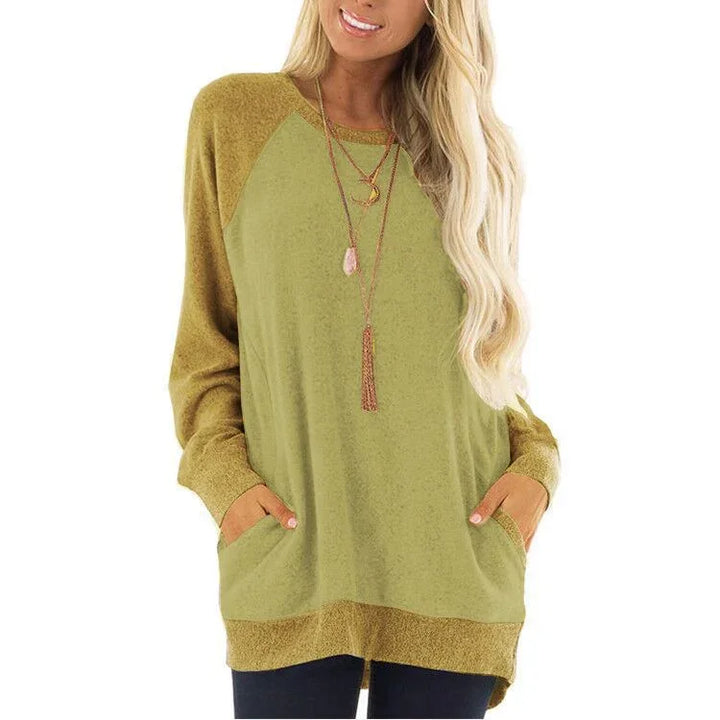 Woman wearing olive green and mustard oversized sweatshirt with pockets and layered necklaces