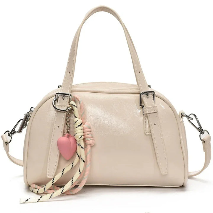Cream leather handbag with detachable shoulder strap and decorative heart charm with rope detail