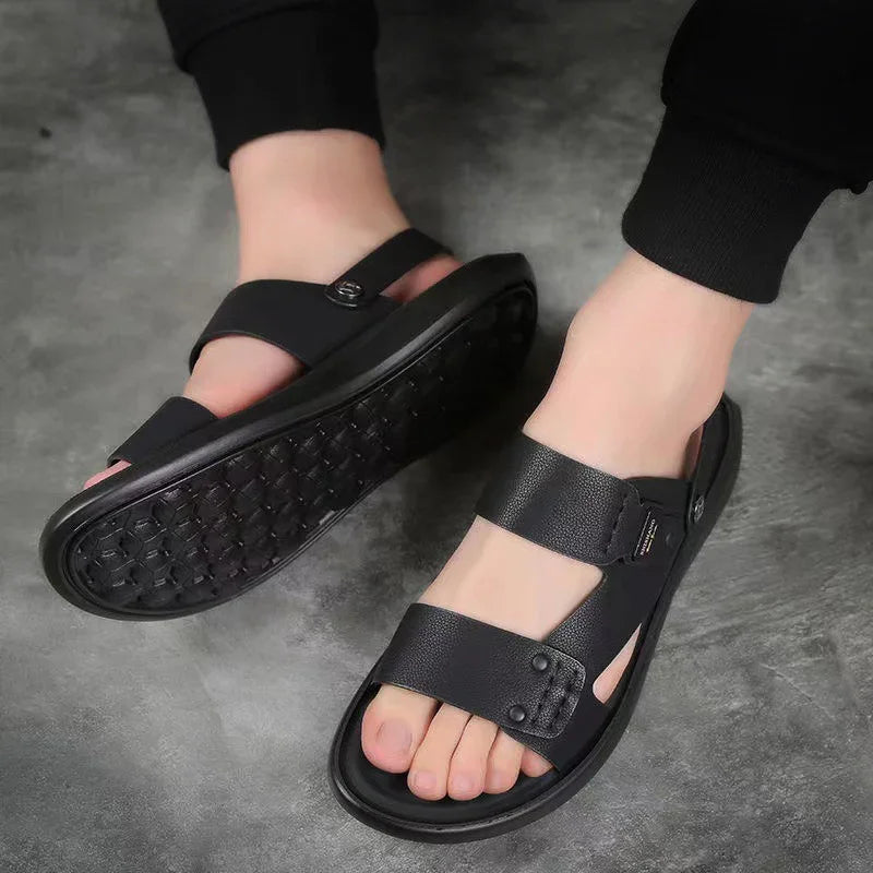 Men's black leather slip-on sandals with adjustable straps on gray floor
