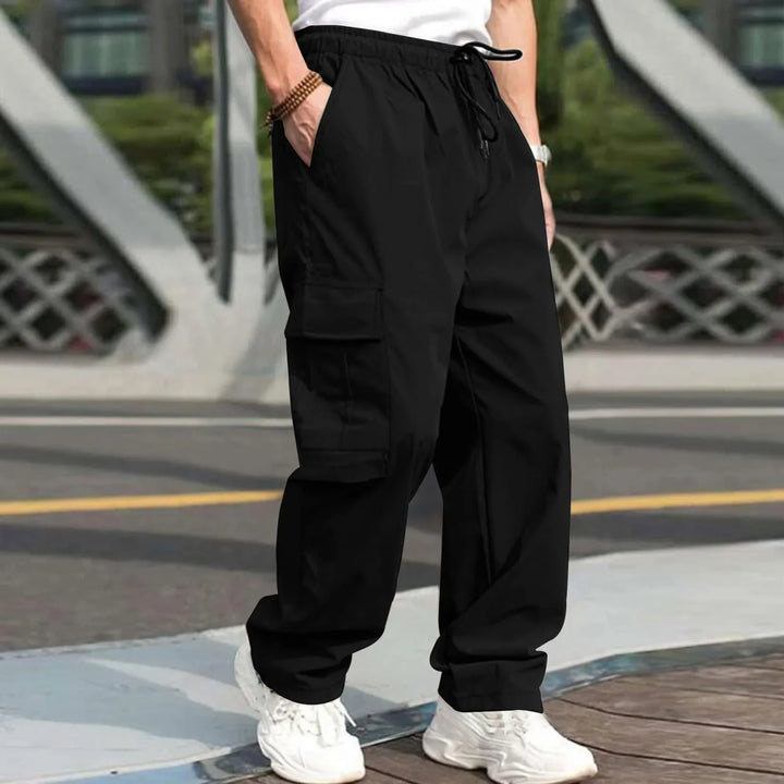 Man wearing black cargo pants and white sneakers standing outdoors on city street