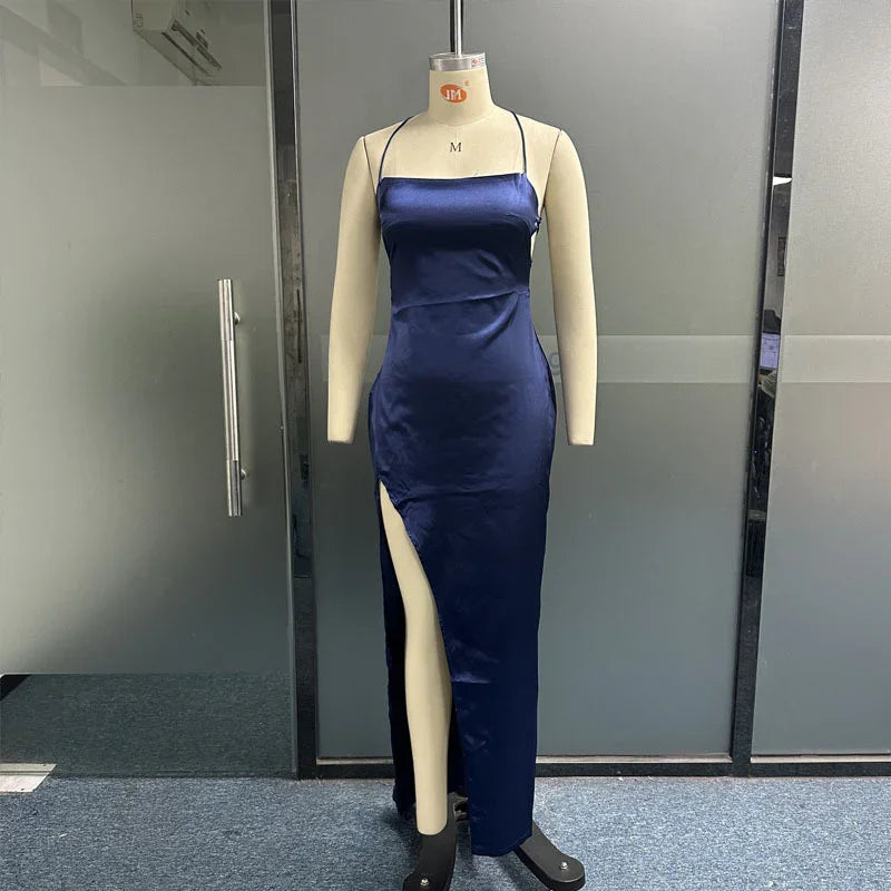 Navy blue satin evening gown with thigh-high slit on dress form in modern office setting