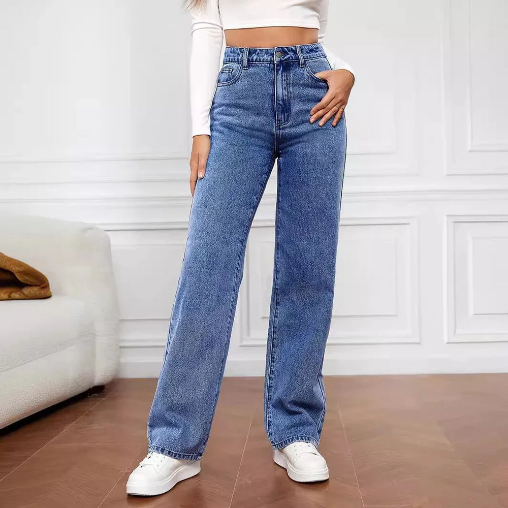 Woman wearing high-waisted blue wide-leg jeans and white sneakers in modern room