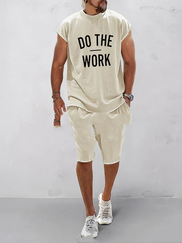Man wearing beige casual sleeveless top with "DO THE WORK" text and matching shorts with white sneakers