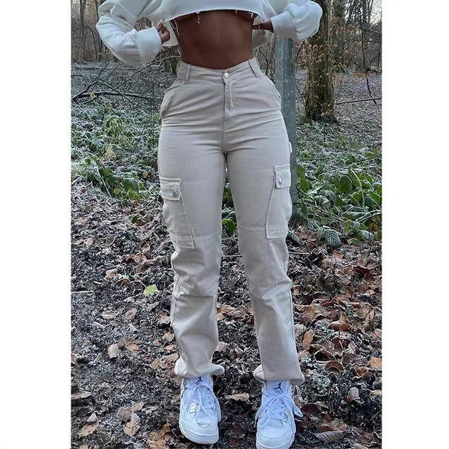 Woman wearing beige cargo pants with pockets and white sneakers standing in a frosty forest