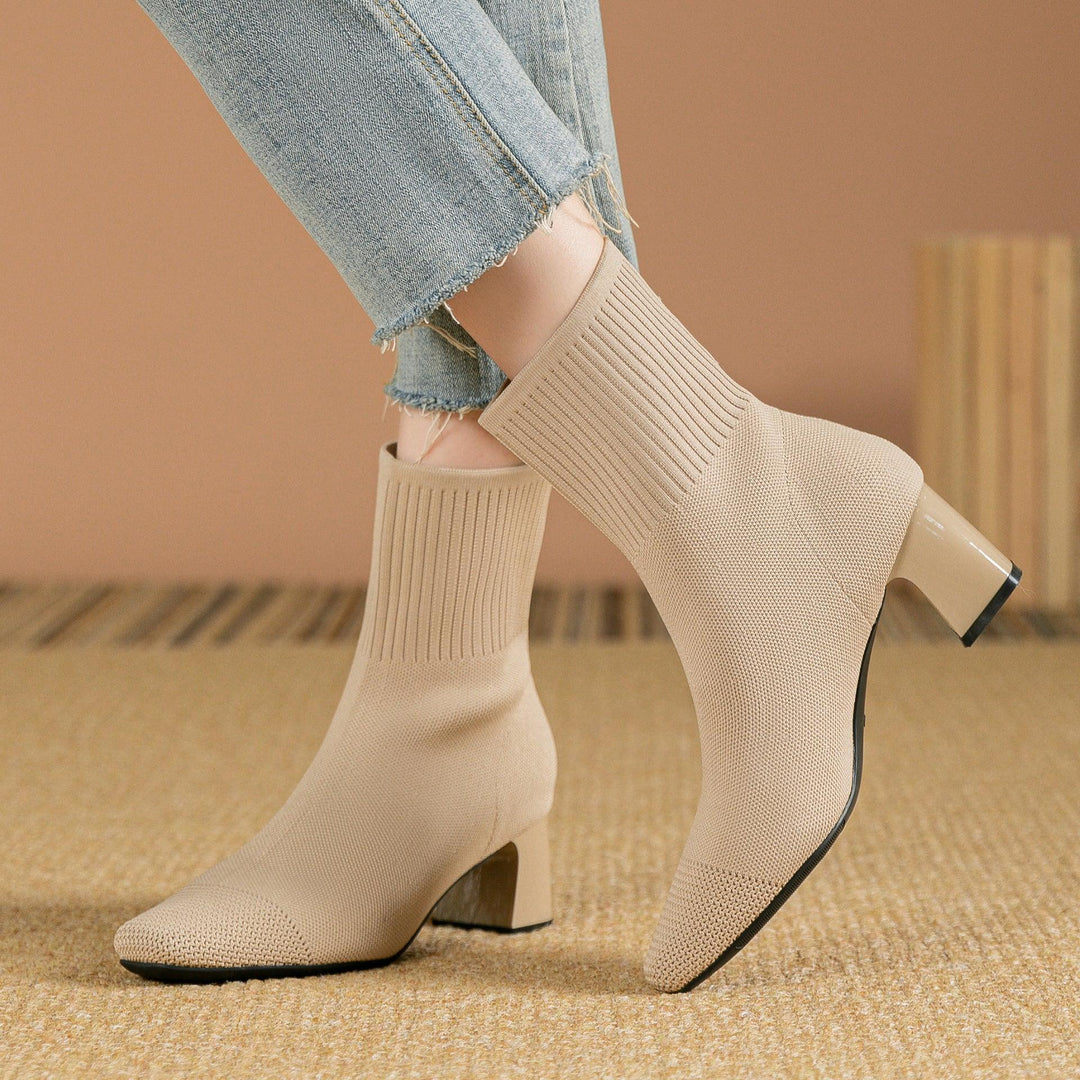 Beige knitted sock boots with block heels worn with light blue frayed hem jeans on a textured floor