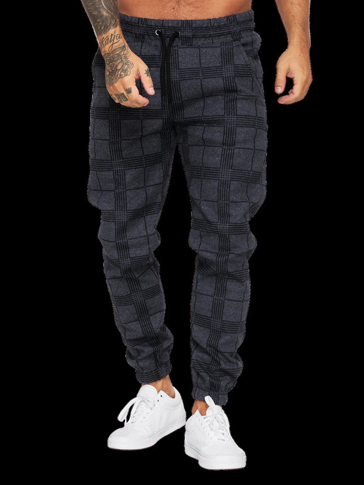 Man wearing dark gray plaid jogger pants with elastic cuffs and white sneakers