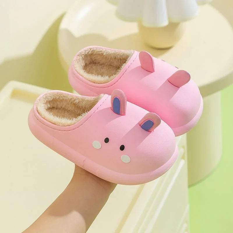 Pink indoor slippers with furry lining and cute bunny ears and face design held by hand