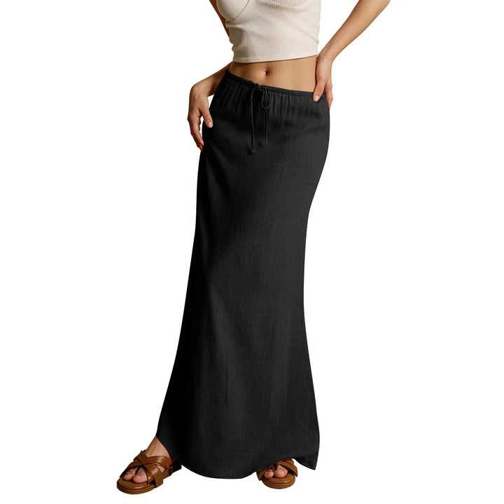 Woman wearing a black drawstring maxi skirt and brown sandals with a cropped white tank top