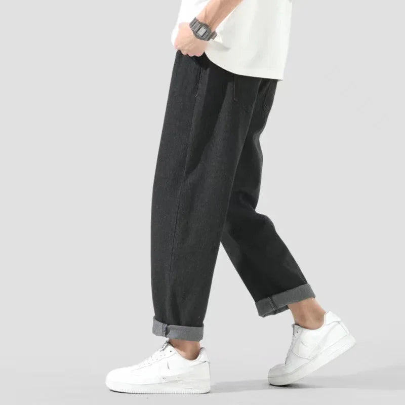 Man wearing black casual pants with rolled cuffs and white sneakers walking