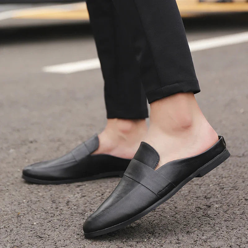 Close-up of black casual slip-on loafers worn with black pants on asphalt street