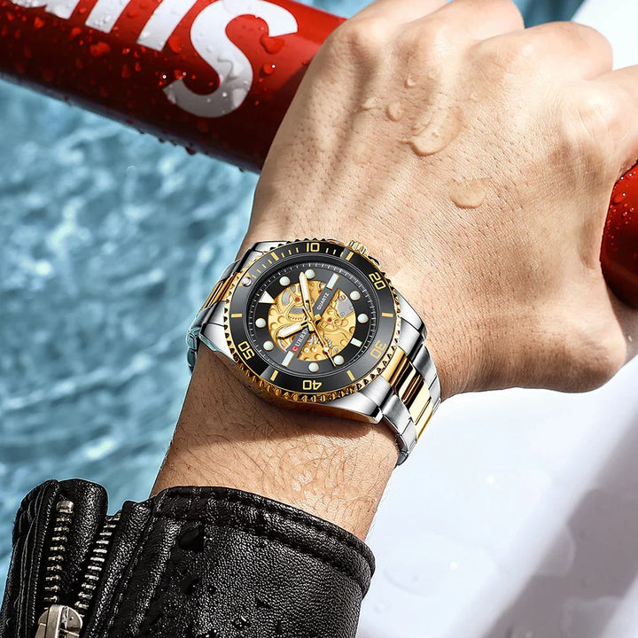 Close-up of wrist wearing two-tone gold and silver mechanical dive watch with black bezel, water droplets on hand