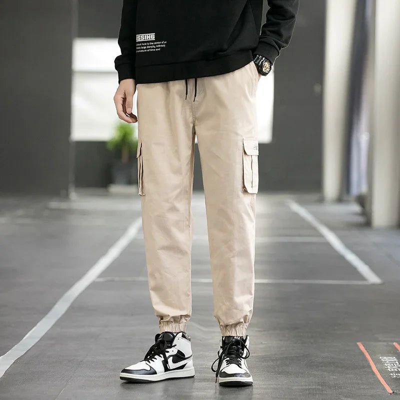 Man wearing beige cargo jogger pants and black white sneakers in urban setting