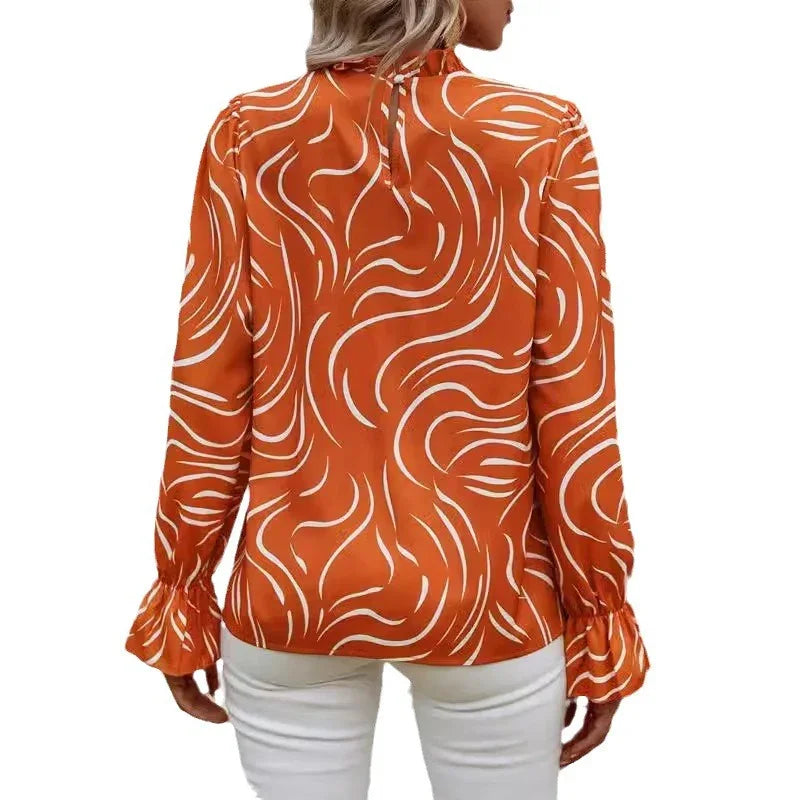 Back view of woman wearing orange blouse with white abstract swirl pattern and ruffled cuffs