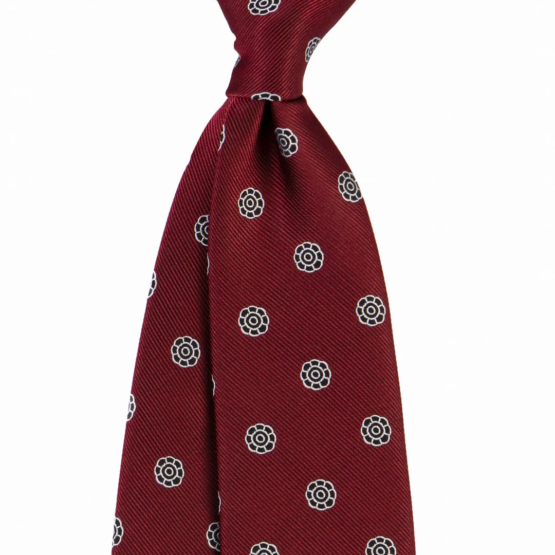 Close-up of a maroon silk necktie with black and white floral dot pattern