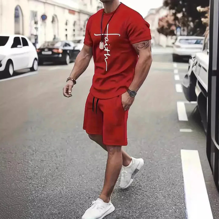 Man in red faith graphic t-shirt and matching shorts walking on city street with white sneakers