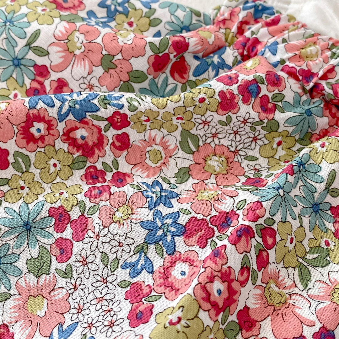 Close-up of fabric with vibrant floral pattern featuring pink, red, blue, and yellow flowers on white background