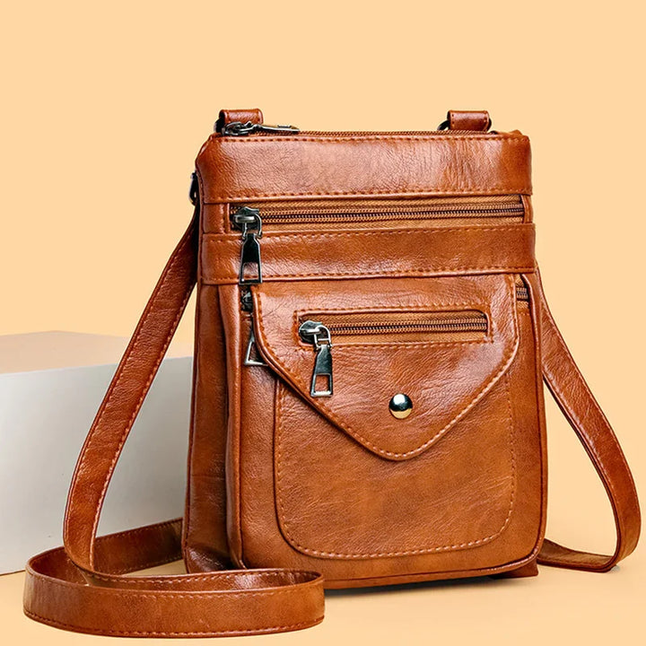 Brown leather crossbody bag with multiple zippered compartments and front flap pocket