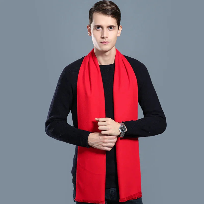 Man wearing a bright red scarf over a black sweater against a gray background