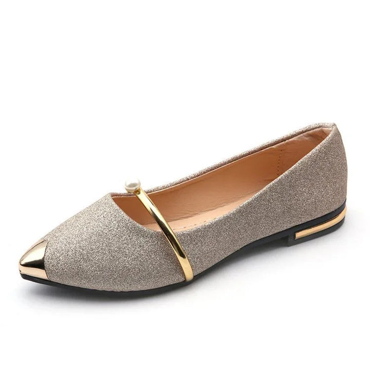 Elegant glittery gold flat shoe with pointed metallic toe cap and decorative gold strap with pearl
