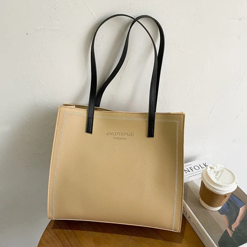 Beige JINGPINPIJU FASHION tote bag with black handles on wooden table next to coffee cup and magazine