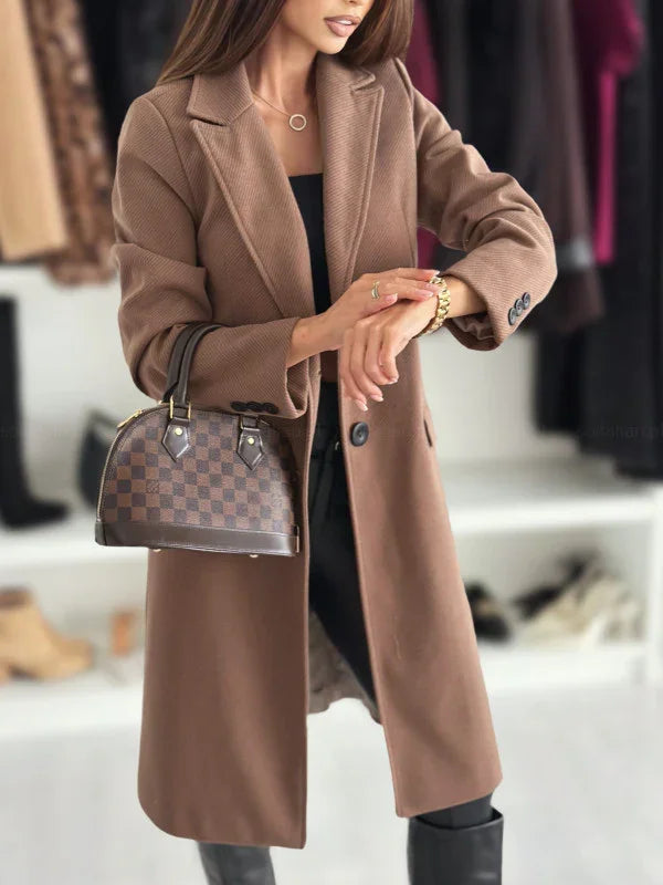 Woman wearing stylish brown overcoat and black outfit, holding designer checkered handbag, adjusting gold watch