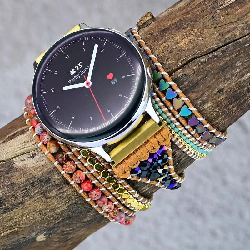 Smartwatch with a modern round black face displaying weather and heart rate, paired with colorful beaded and braided multi-layer bracelets on wooden surface
