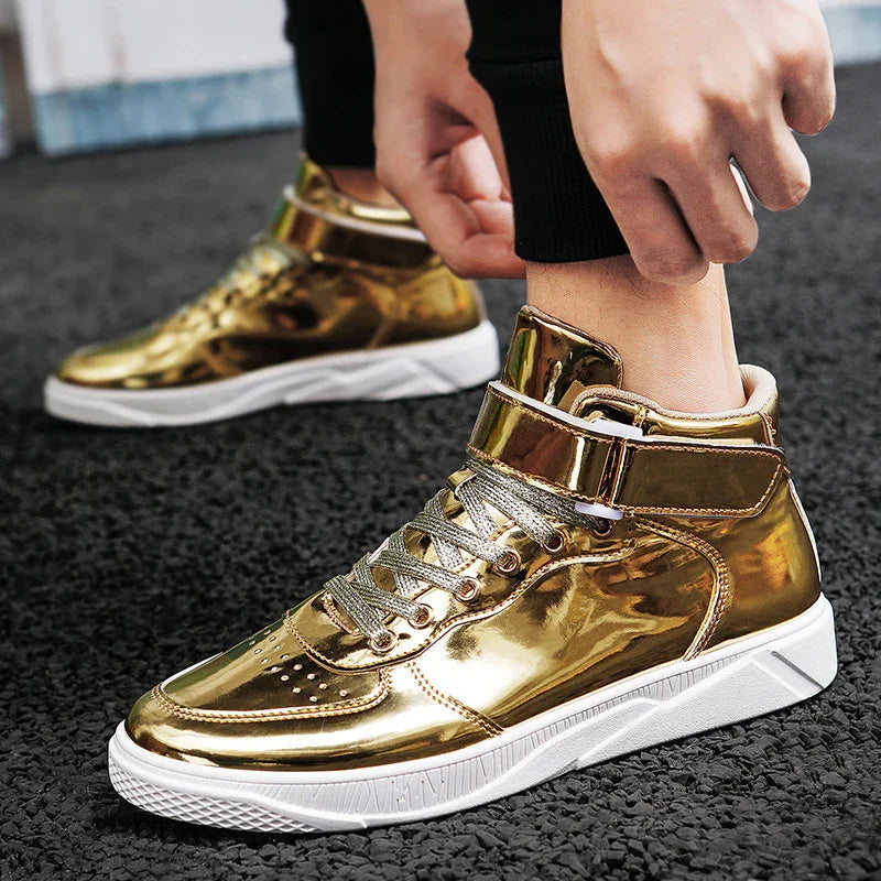 Shiny gold high-top sneakers with white soles on black textured ground, person wearing black pants