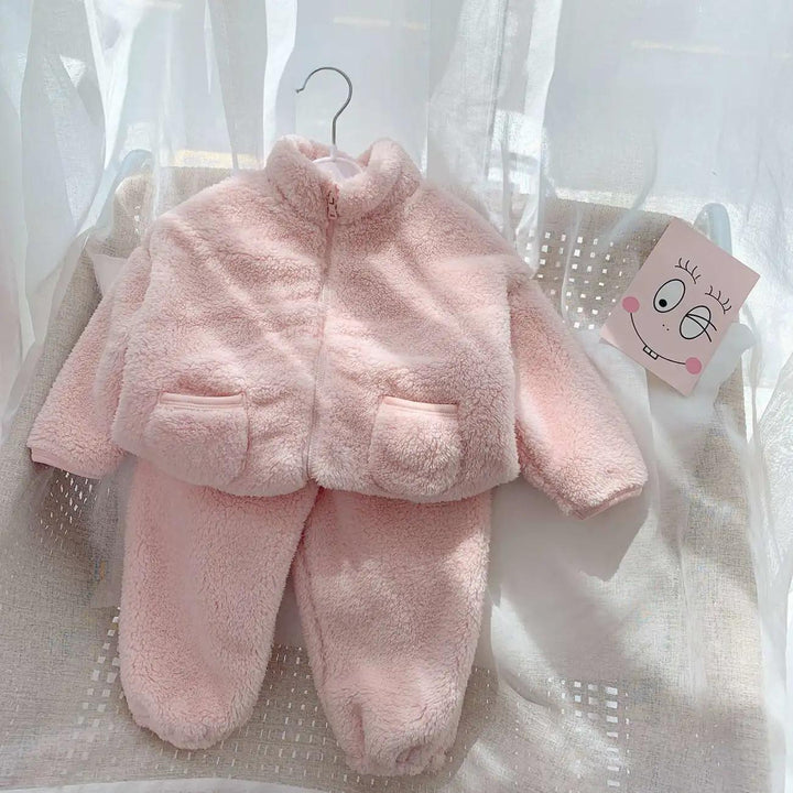 Soft pink fuzzy toddler jacket and pants set displayed on a chair with sheer curtains