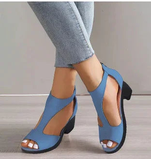 Woman wearing stylish blue open-toe sandals with cutout design and low block heels, paired with cropped jeans