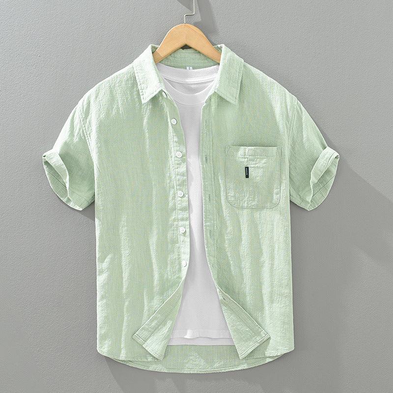 Light green short-sleeve button-up shirt with chest pocket over white t-shirt on wooden hanger