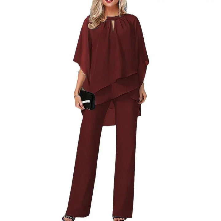 Woman wearing elegant dark red layered tunic with wide-leg pants and black clutch purse