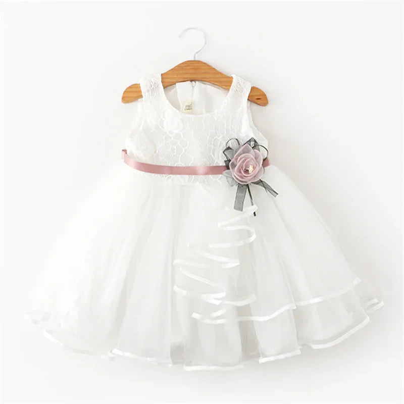 White sleeveless baby dress with lace bodice, pink satin waist ribbon, and decorative flower